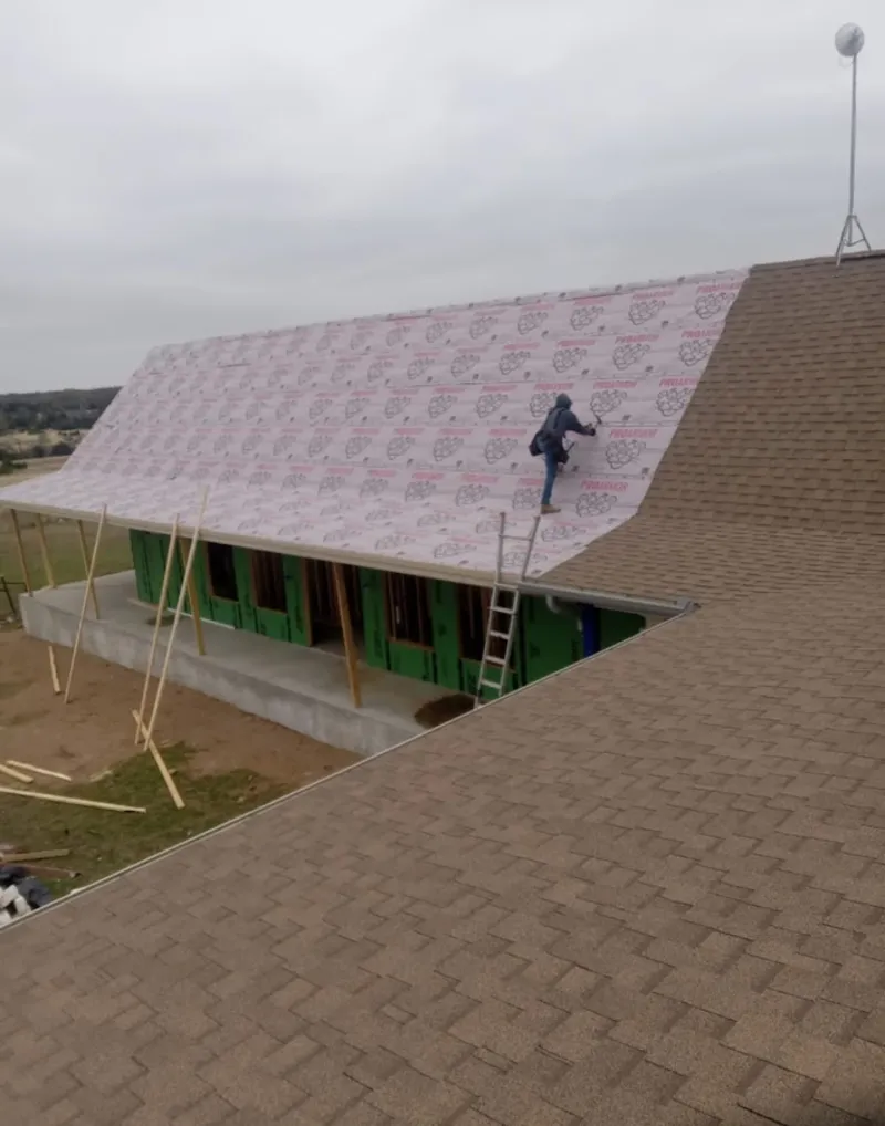 Worker preparing underlayment for a metal roof installation in Cleveland